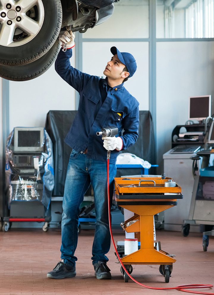 Technician working on car that is raised overhead